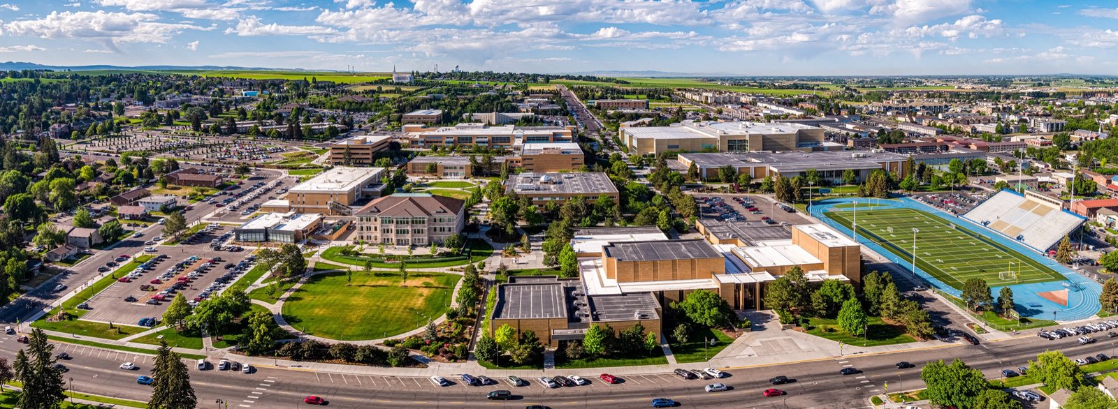 Aerial panorama of the BYU-Idaho campus in Rexburg on a sunny day, including the stadium and surrounding buildings.