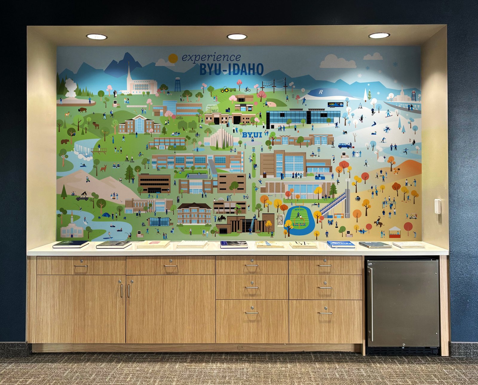 The finished map graphic installed on a lit wall in the BYU-Idaho Welcome Center, above a counter of brochures.